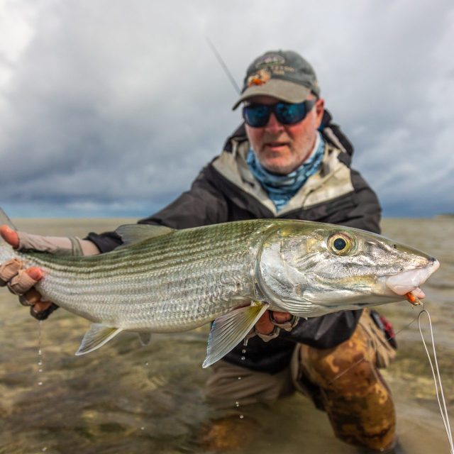 Angler bonefishing in cloudy, rainy conditions with reduced visibility
