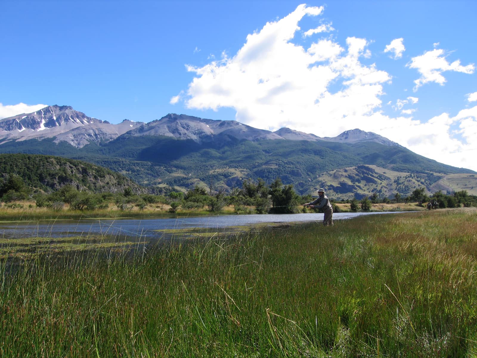 Anglers on the Ñirehuao River below snowy peaks at El Saltamontes Lodge, Chile