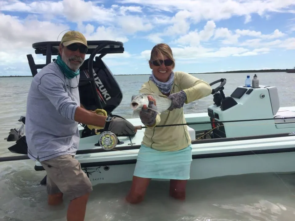 Anglers holding a bonefish beside a flats skiff at Grey’s Point Inn, Acklins Island, Bahamas