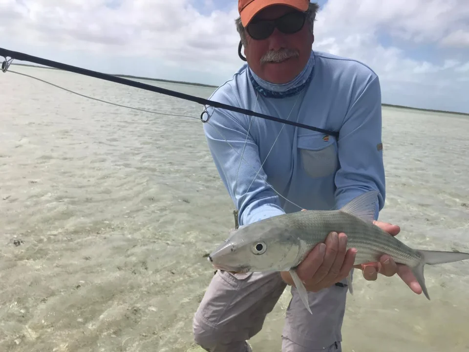 Angler holding a bonefish while wading the flats at Grey’s Point Inn, Acklins Island, Bahamas