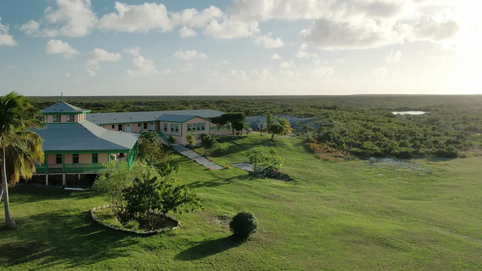 Pink lodge buildings with green railings on the lawn at Grey’s Point Inn, Acklins Island, Bahamas