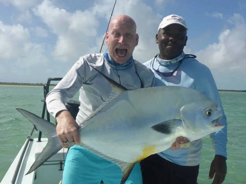 Angler and guide holding a permit on a flats skiff at Grey’s Point Inn, Acklins Island, Bahamas