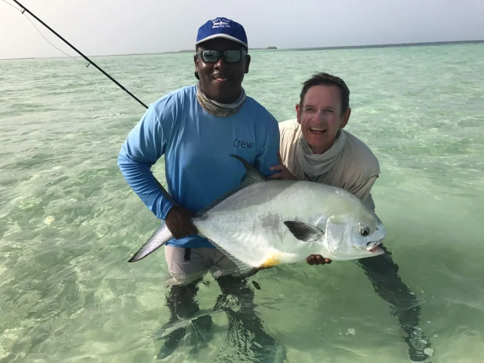Guide and guest holding a permit while wading Acklins Island flats at Grey’s Point Inn, Bahamas