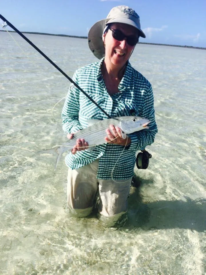 Woman angler holding a bonefish while wading Acklins Island flats at Grey’s Point Inn, Bahamas