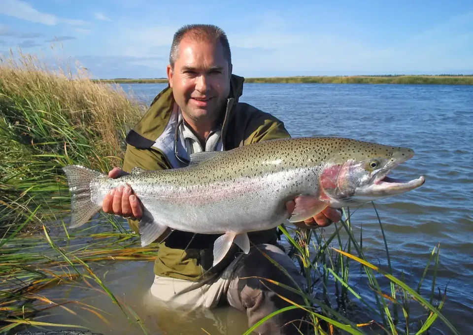 Angler with trophy rainbow trout wading — Royal Coachman Lodge, Nuyakuk River, Bristol Bay, Alaska