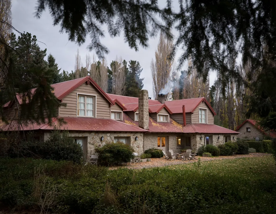 Tipiliuke Lodge in autumn, stone and wood lodge with red roof, Chimehuín River, Patagonia, Argentina