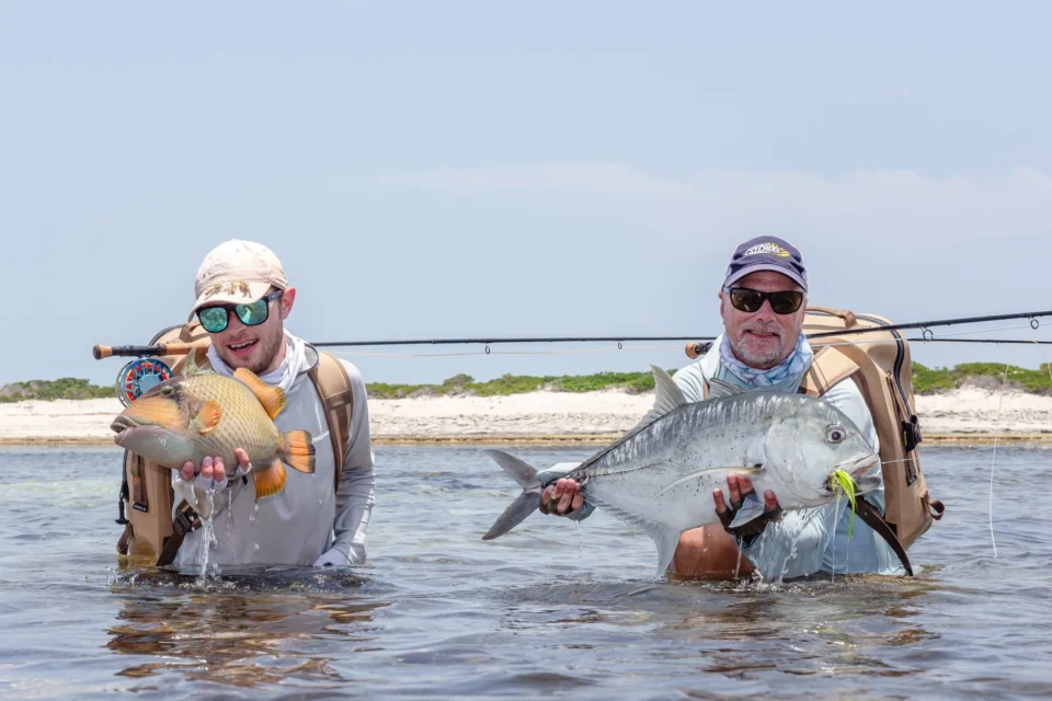 Two anglers with a triggerfish and a giant trevally — Astove Atoll, Seychelles