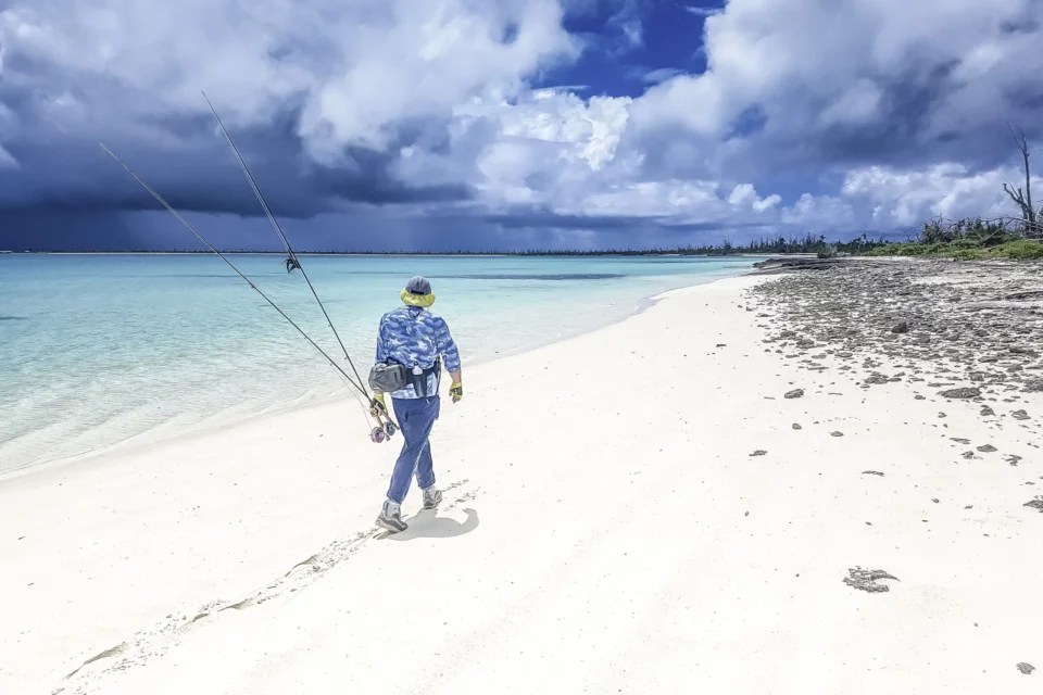 Angler walking the beach with a fly rod — Farquhar Atoll, Seychelles
