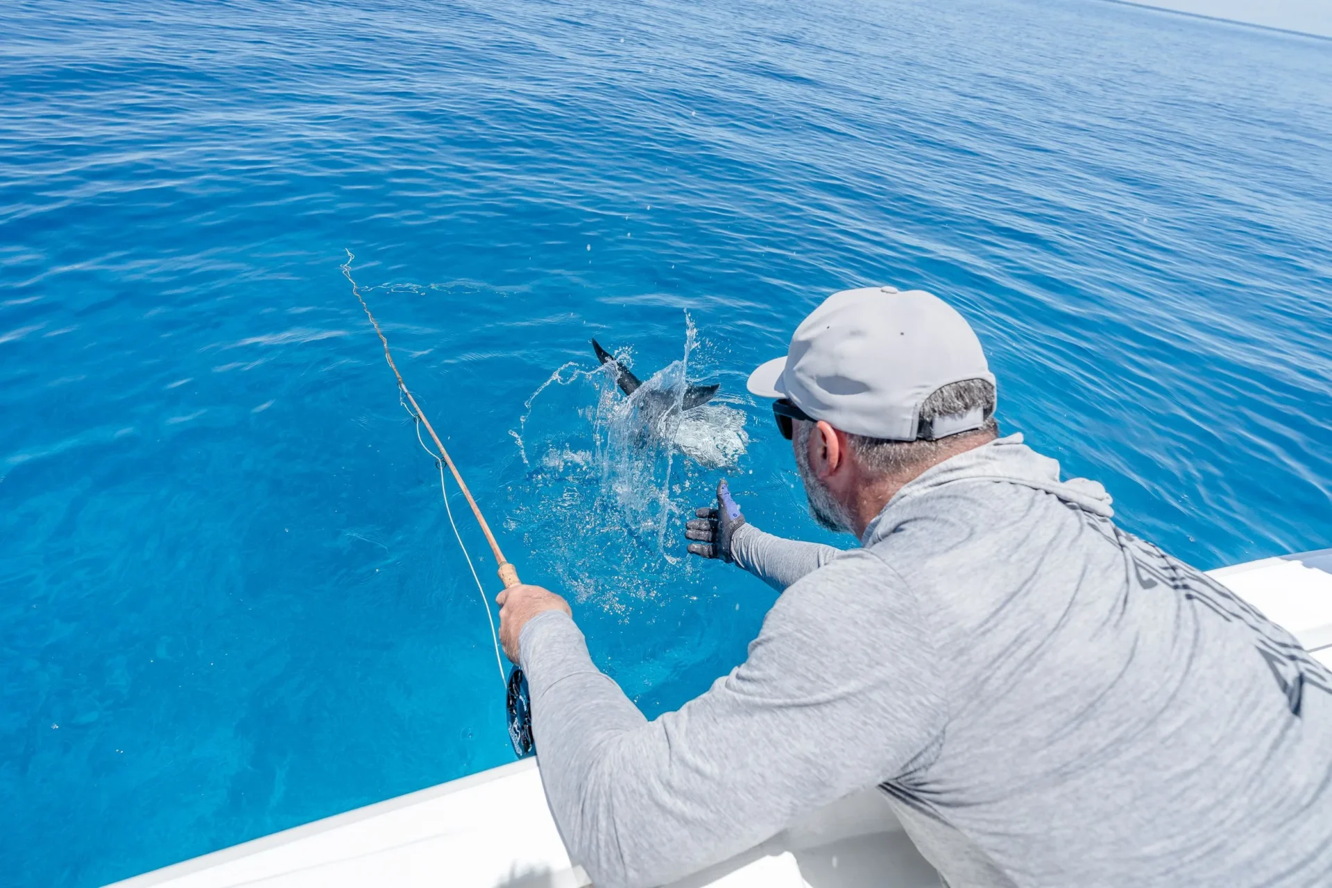 Angler fighting a fish in blue water — Providence Atoll, Seychelles