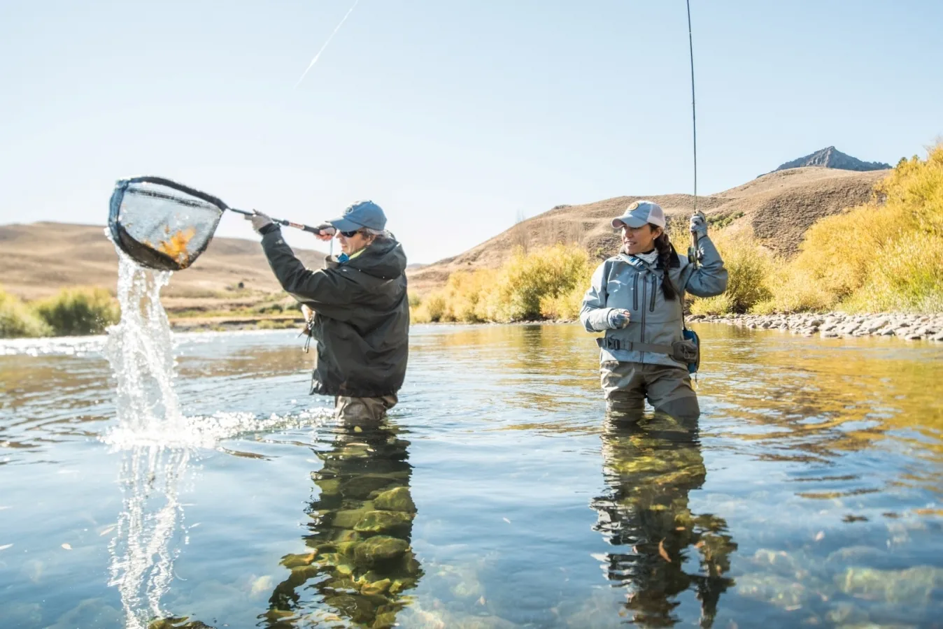Anglers landing a trout in a net on the Chimehuín River at Tipiliuke Lodge, Patagonia, Argentina