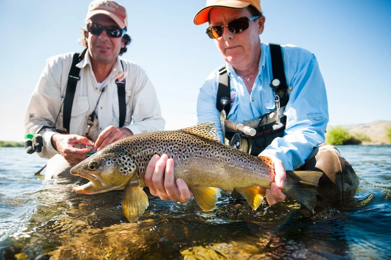 Two anglers holding a large brown trout in the Chimehuín River at Tipiliuke Lodge, Patagonia, Argentina