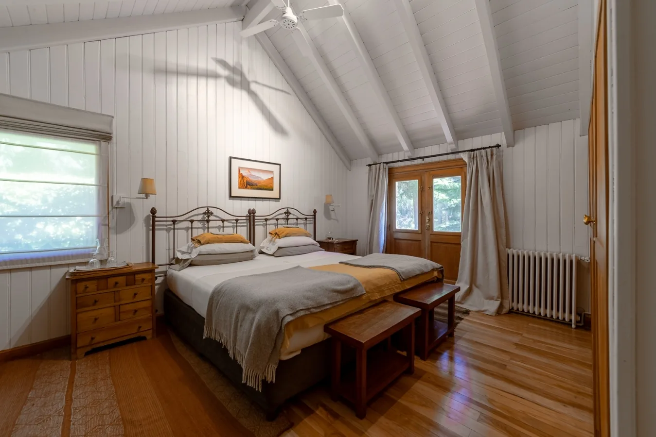 Guest bedroom with twin beds, white paneling, and garden doors at Tipiliuke Lodge, Patagonia, Argentina