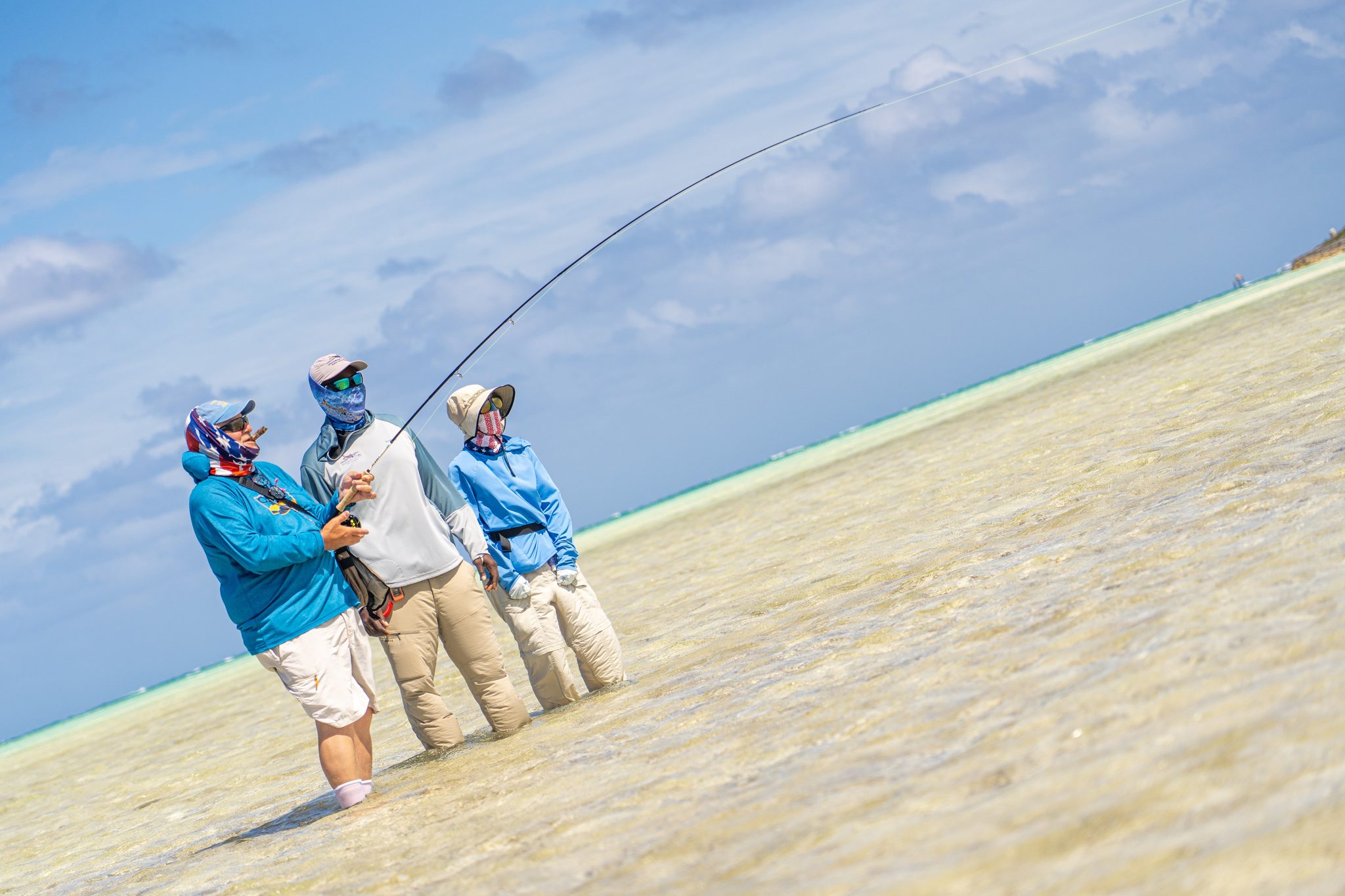 Anglers on the Andros flats with a bent fly rod, working a hooked bonefish. Photo Adam Campesi, Campesi Design.