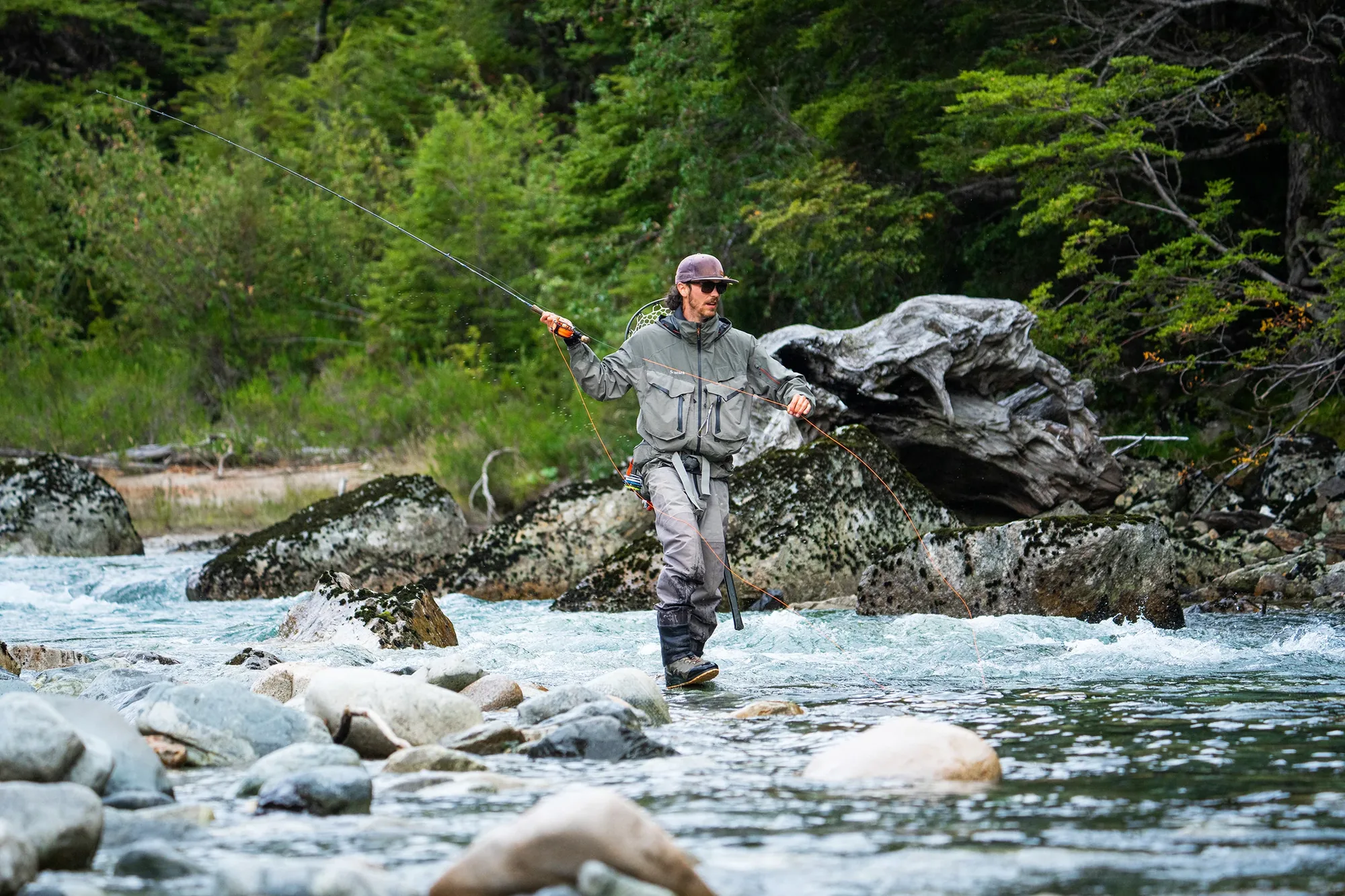 Angler wading a rocky river with a fly rod near Eleven Rio Palena Lodge, Chile