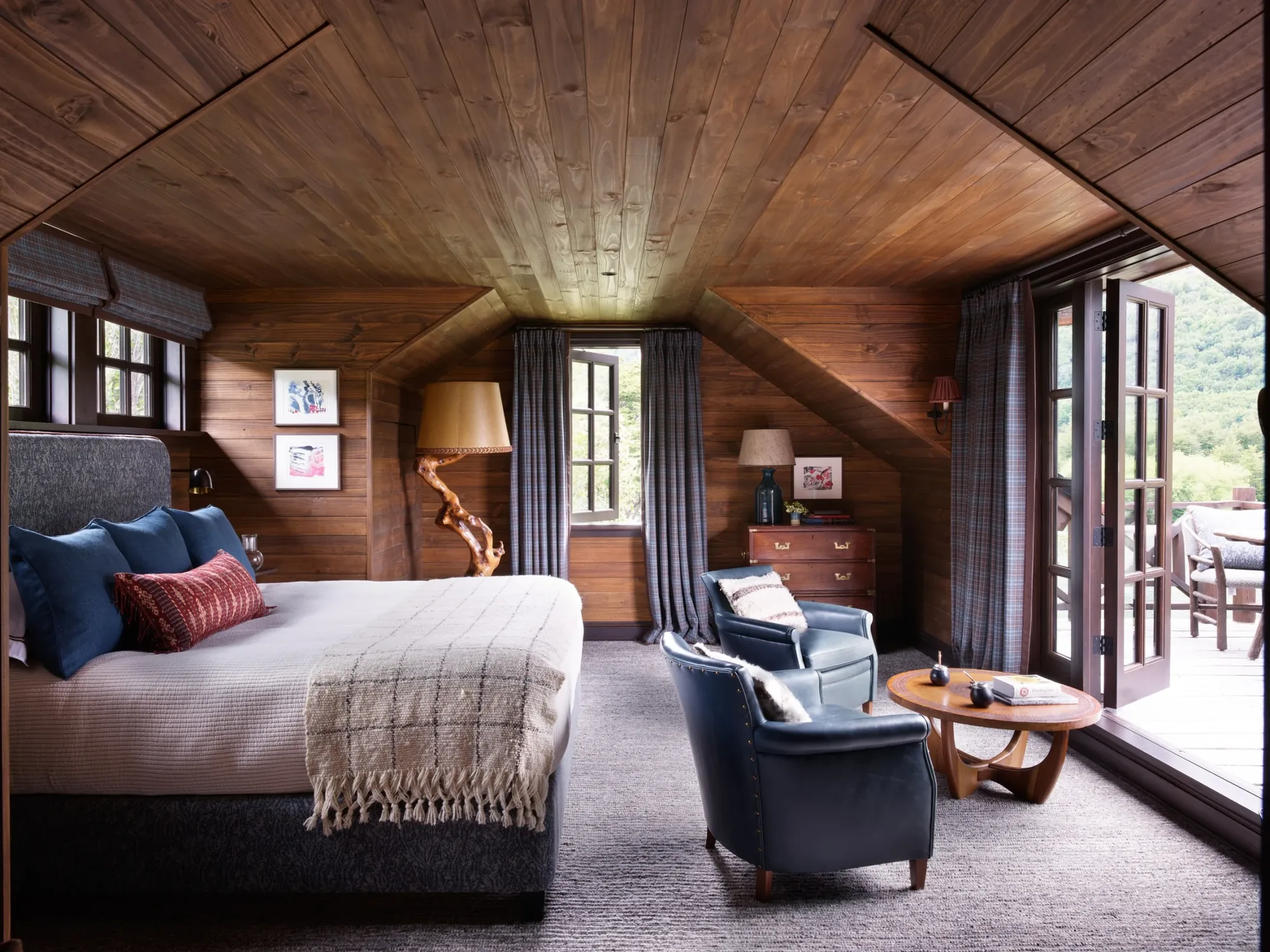 Wood-paneled king guest room opening onto a deck at Eleven Rio Palena Lodge, Chile