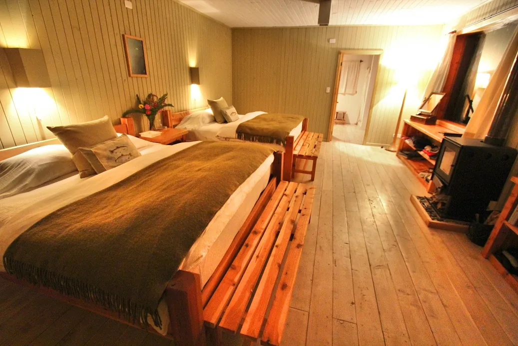 Wood-paneled bedroom with a wood stove at Futa Lodge, Chile