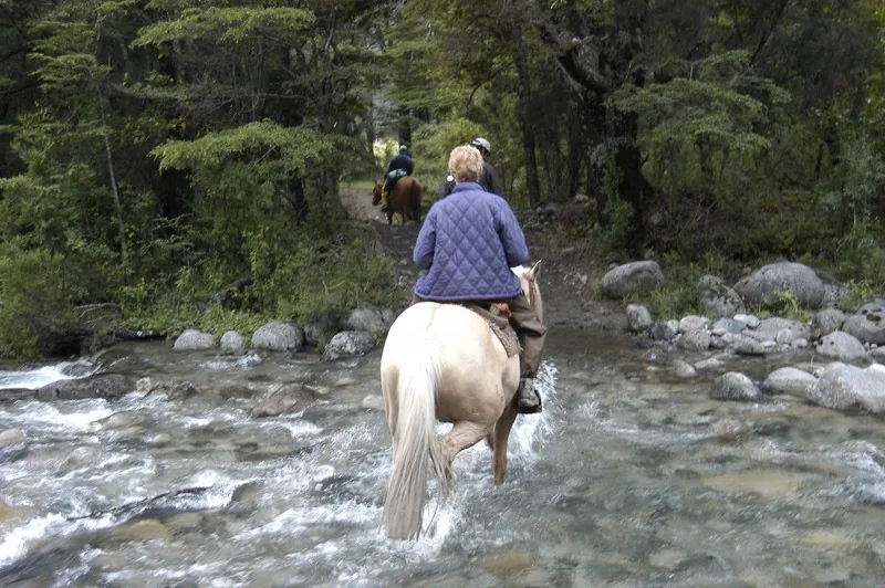 Riders on horseback crossing a river near Futa Lodge, Chile