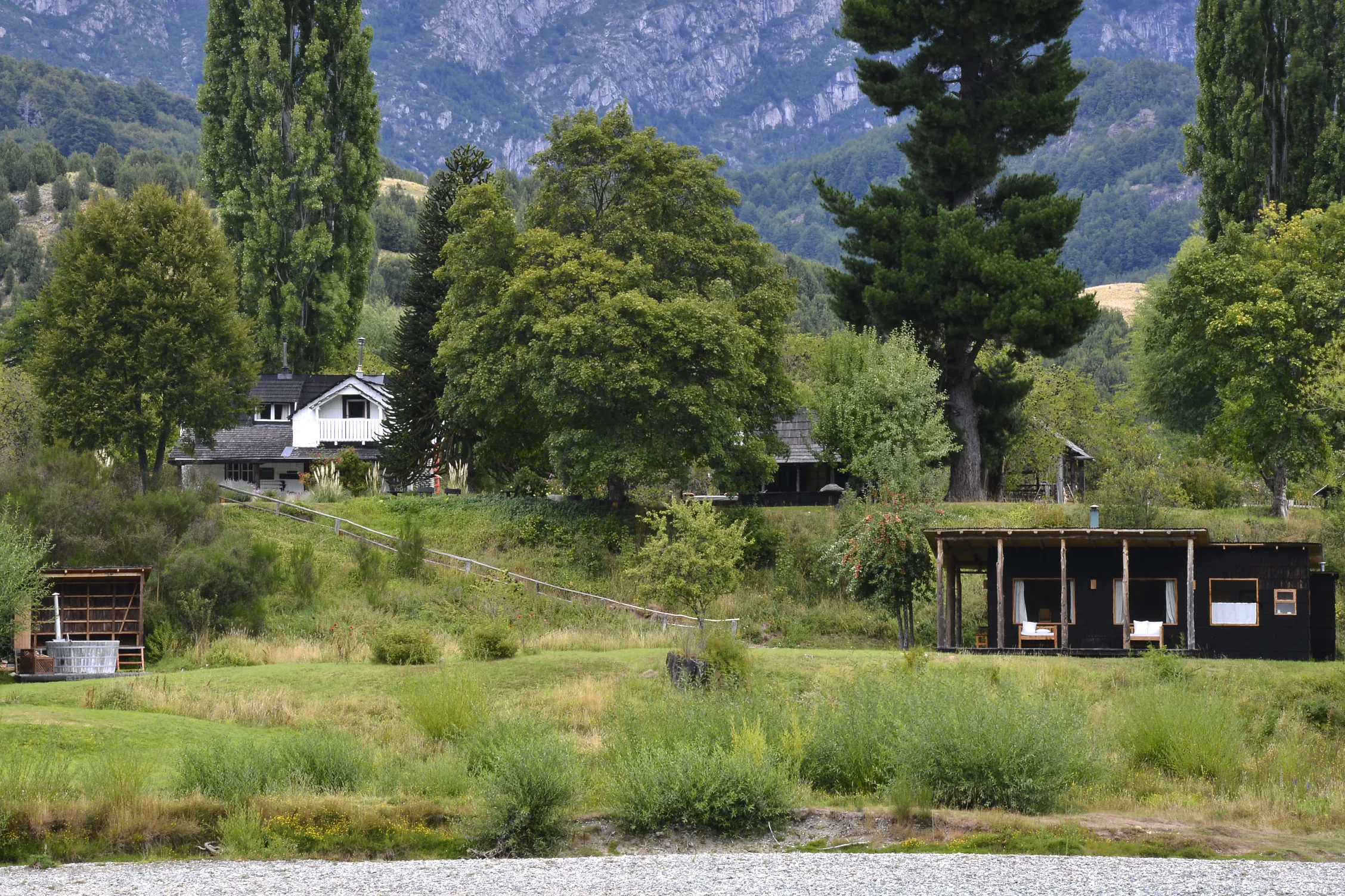 Riverside cabins and the lodge house on the meadow at Futa Lodge, Futaleufú, Chile