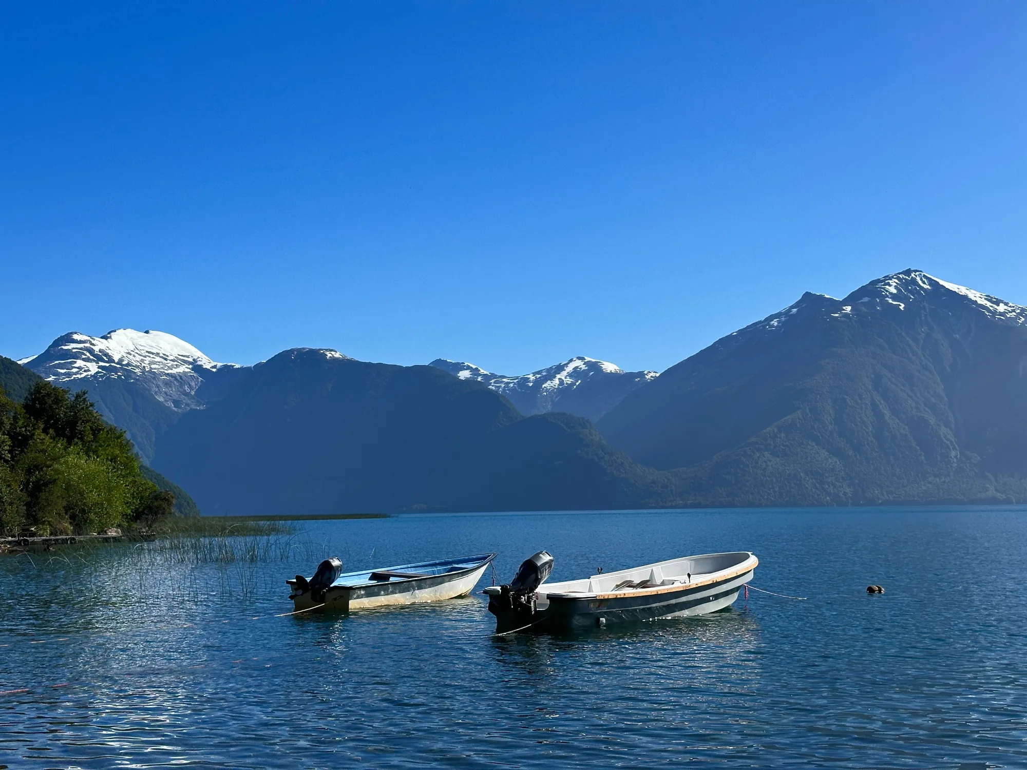 Two fishing skiffs on Lago Yelcho below snowy peaks, Chile