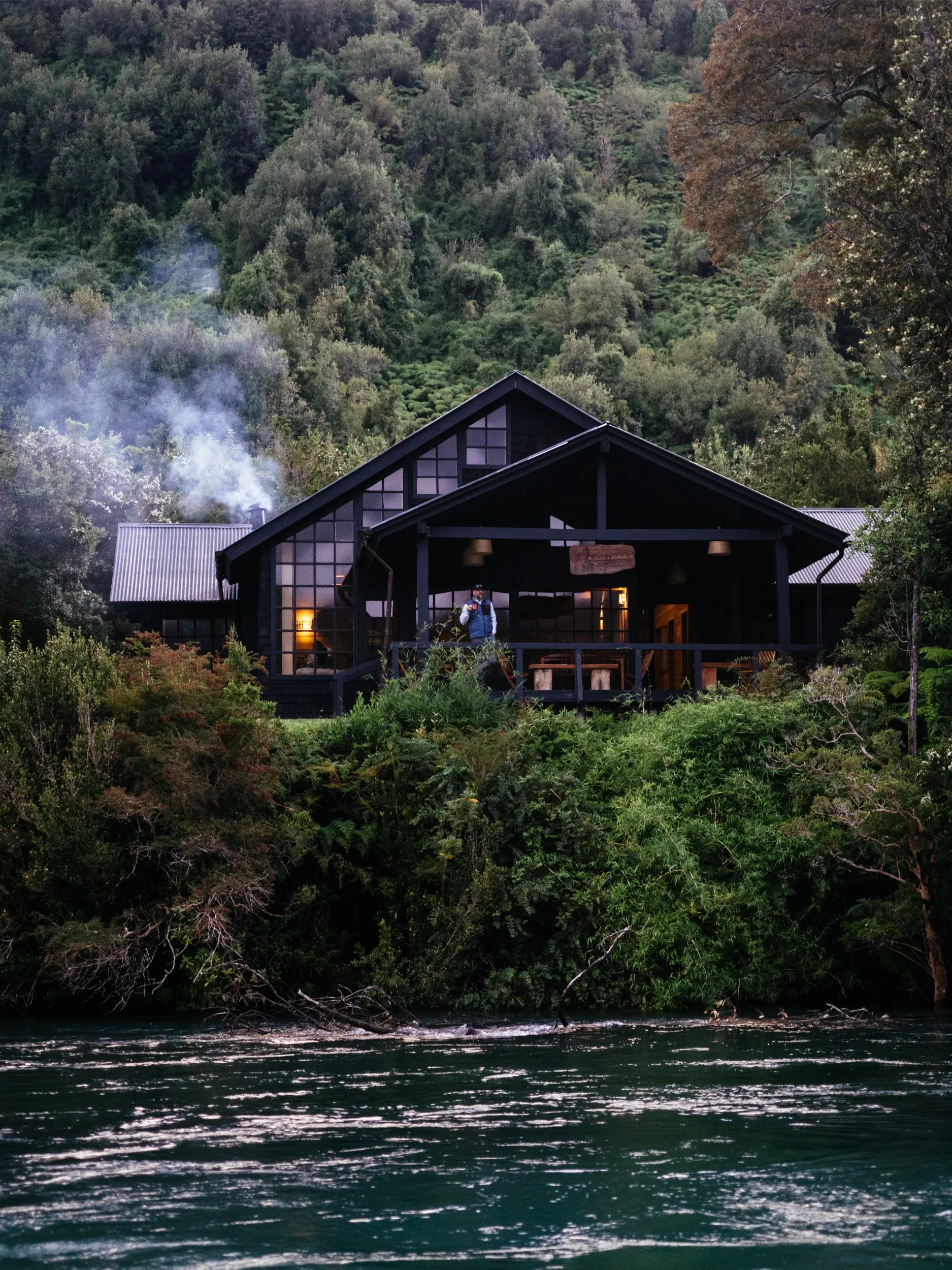 Dark wood lodge above the river in Valdivian forest at Eleven Martín Pescador, Chile