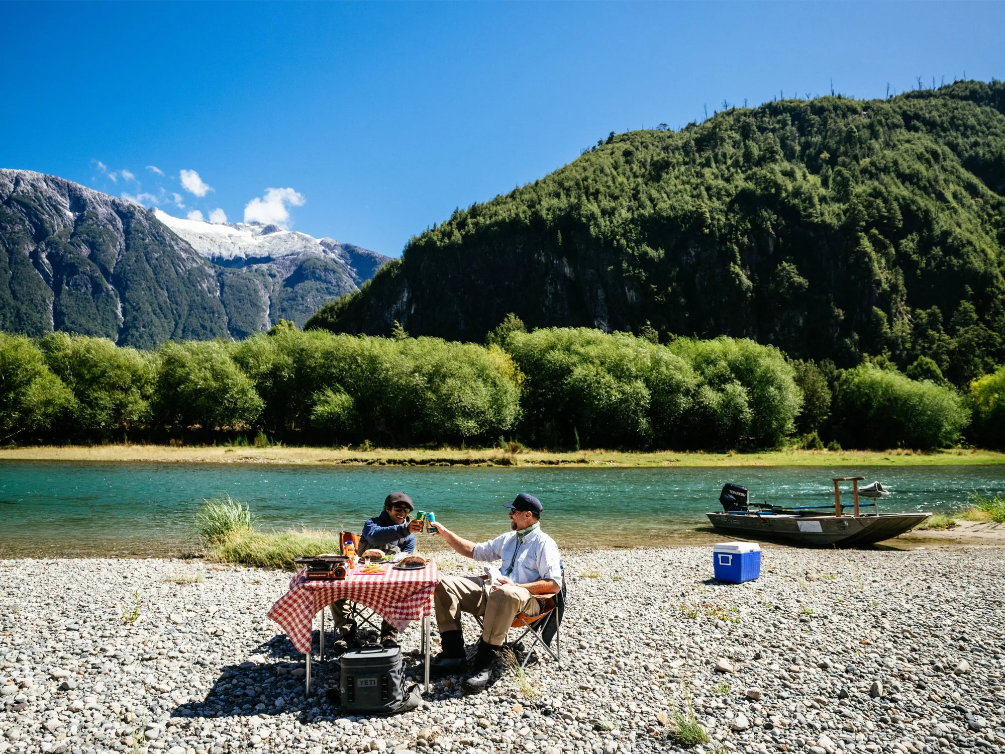 Riverside lunch on a gravel bar with a skiff pulled up, Eleven Martín Pescador, Chile
