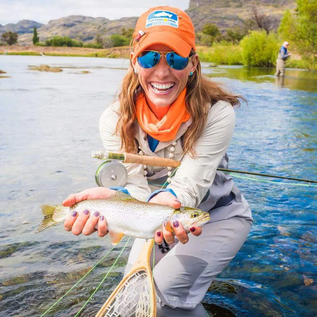 Smiling angler holding a trout in a river at El Saltamontes Lodge