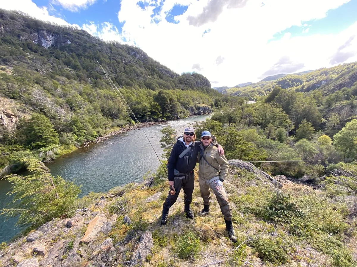Two anglers on a hillside above a winding river valley near El Saltamontes Lodge