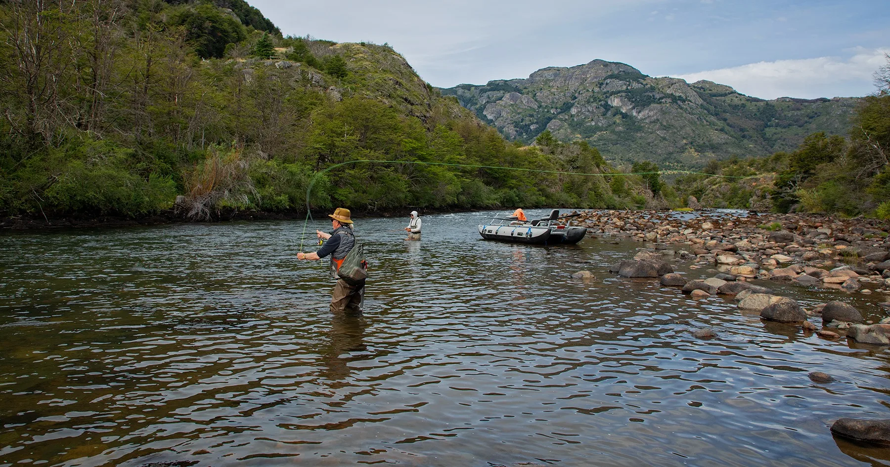 Anglers wading beside a raft on a Patagonia river during an El Saltamontes float trip