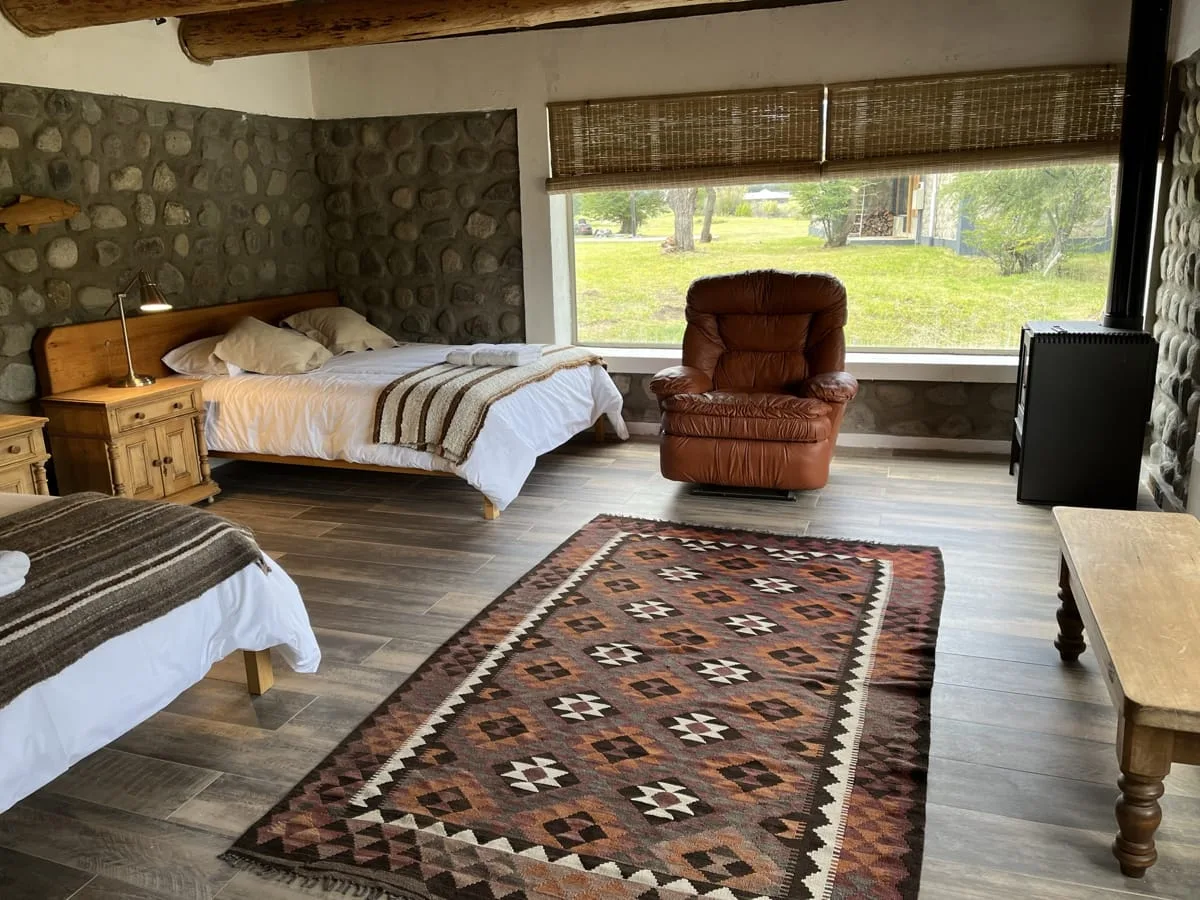 Guest room with a wool rug and a big window to the valley at El Saltamontes Lodge
