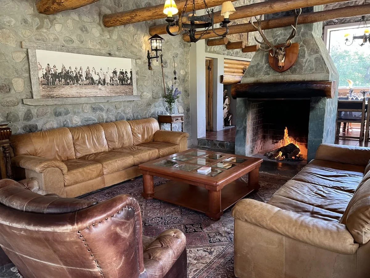 Living room with leather chairs around a fireplace at El Saltamontes Lodge