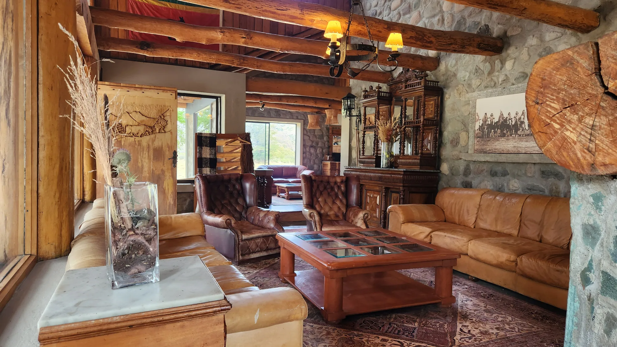 Main lodge lounge with log beams and leather sofas at El Saltamontes Lodge