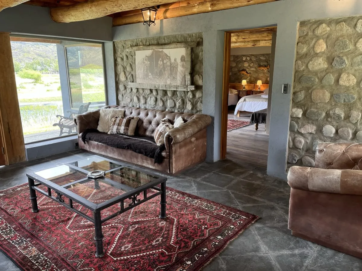 Sitting room with leather sofa and stone walls at El Saltamontes Lodge