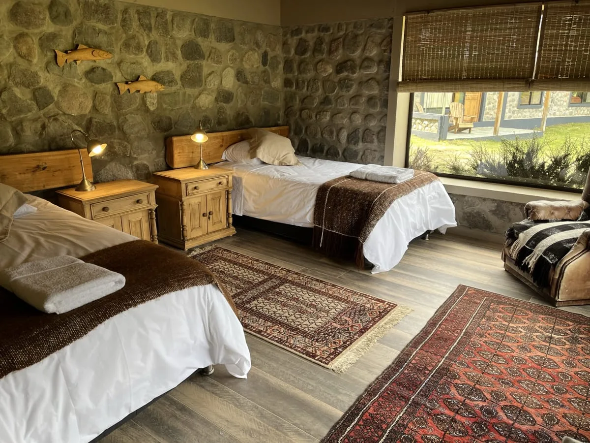 Twin guest room with stone walls and wood floors at El Saltamontes Lodge