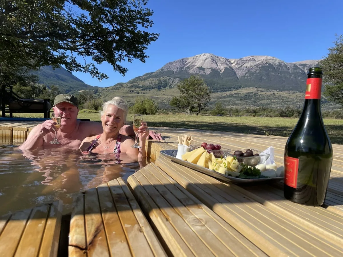 Guests in the wood-fired hot tub with wine and mountain views at El Saltamontes Lodge