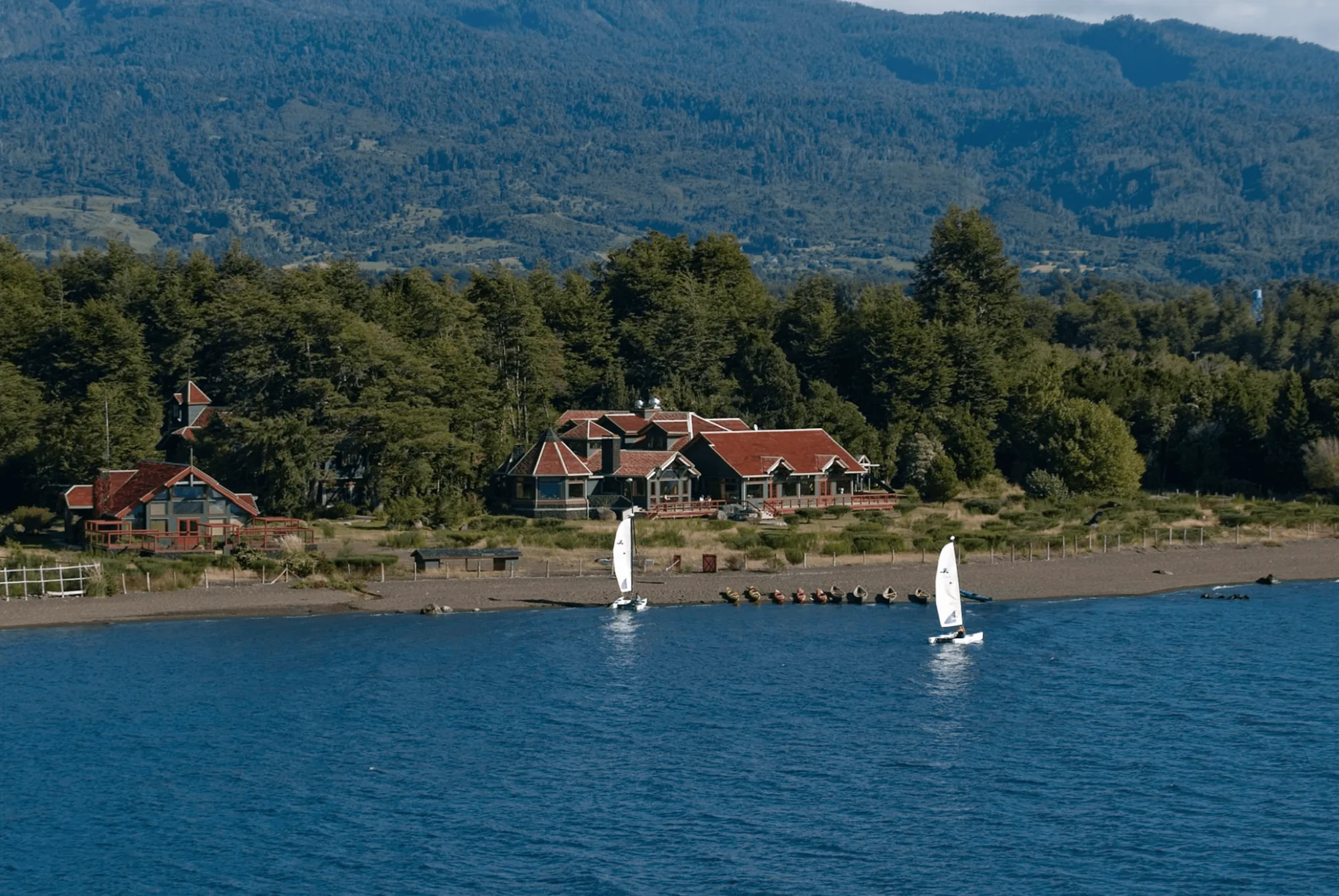 Yan Kee Way Lodge on the shore of Lago Llanquihue in Ensenada, Chile, with sailboats offshore